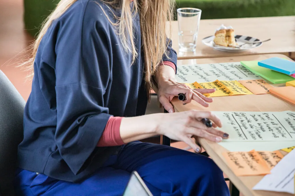 ARTCOM-Workshop am KIT: Teilnehmerin arbeitet mit handschriftlichen Karten an einem Tisch